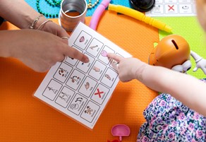 Image of a child and staff member using a paper with images and words on to communicate